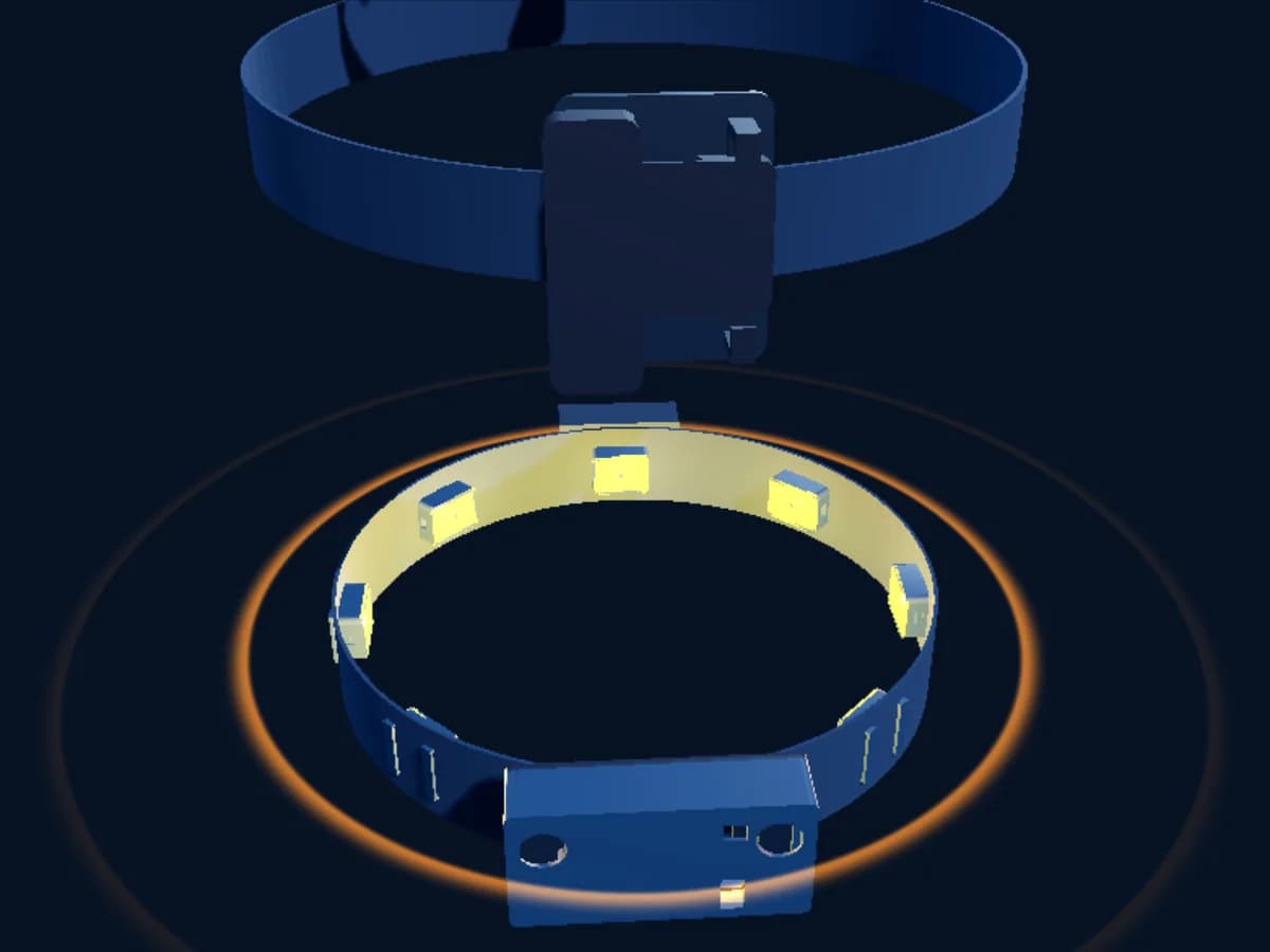 The second generation kit: a waist belt with eight motor pods and the sensor pod at the front, a collar strip with four, and two ankle bands with four each, lit by one warm amber light on deep blue.